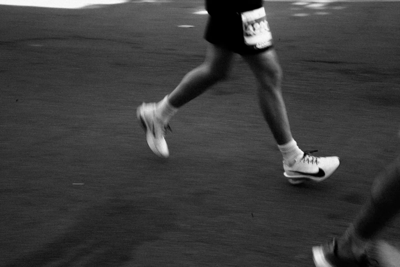 Close-up of a runner's legs and feet mid-stride on a road.